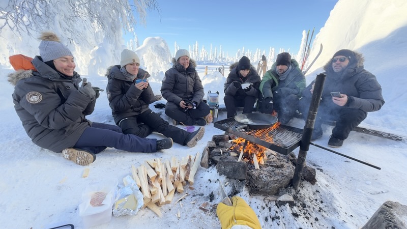 Le groupe assis dans la neige autour d'un feu de camp